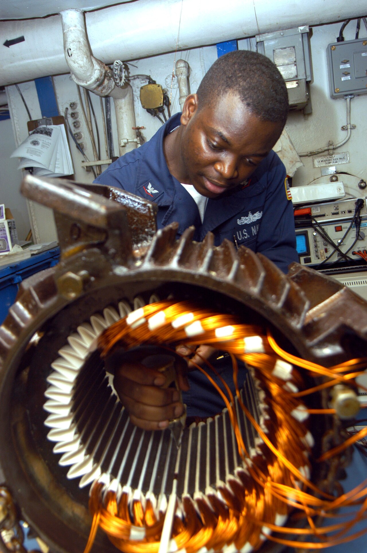US Navy 040902-N-7683J-003 Electrician's Mate 3rd Class Tayo Gbadebo from Lagos, Nigeria, rewires the motor from an Aqueous Film Forming Foam (AFFF) Sprinkler System's pump